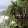 Students standing on observation deck look out at massive waterfalls