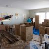 Man surveys a living room filled with tarps and packing boxes