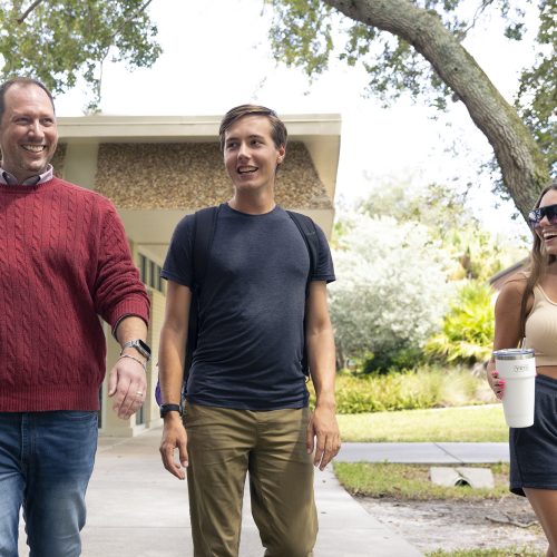 Professor walks down pathway with two students while engaged in conversation