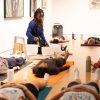 Woman plays crystal bowls as students lie on yoga mats around her