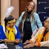 Three people sharing a laugh, one of whom is dressed in Native American attire