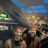 Two students stand inside a very large domed room with a whale statue hanging from ceiling