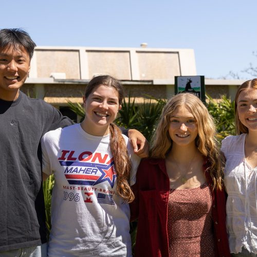 Four students stand with arms over shoulders