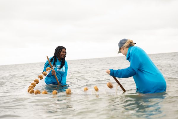 Two students holding large net in the water