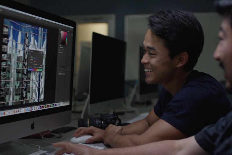 Student and professor smiling while looking at video editing software on a computer screen