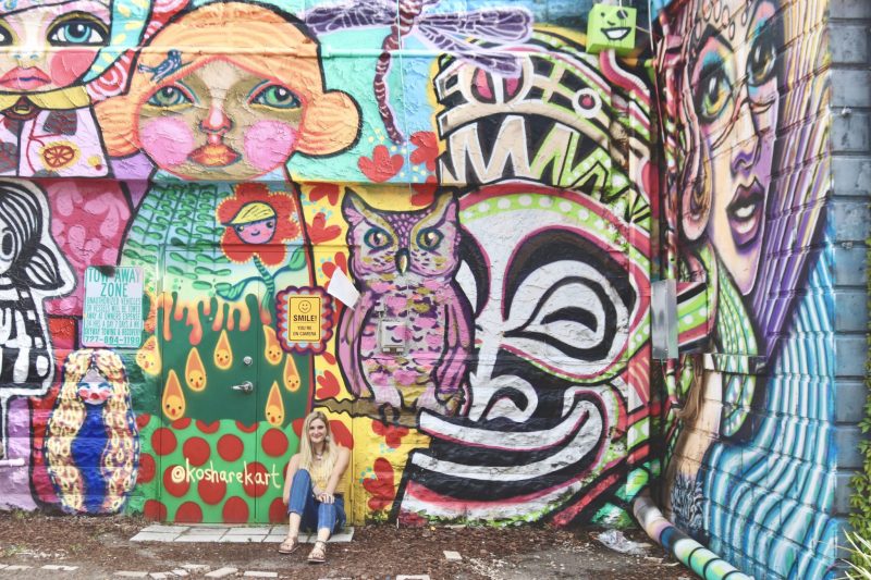 Student seated outside against large walls covered in murals